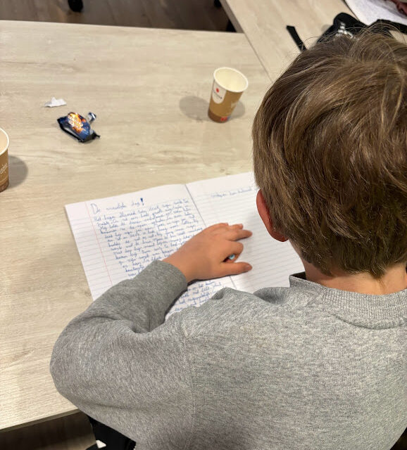 Een kind schrijft geconcentreerd aan zijn verhaal bij Pennenhelden - Schrijfclub voor kinderen